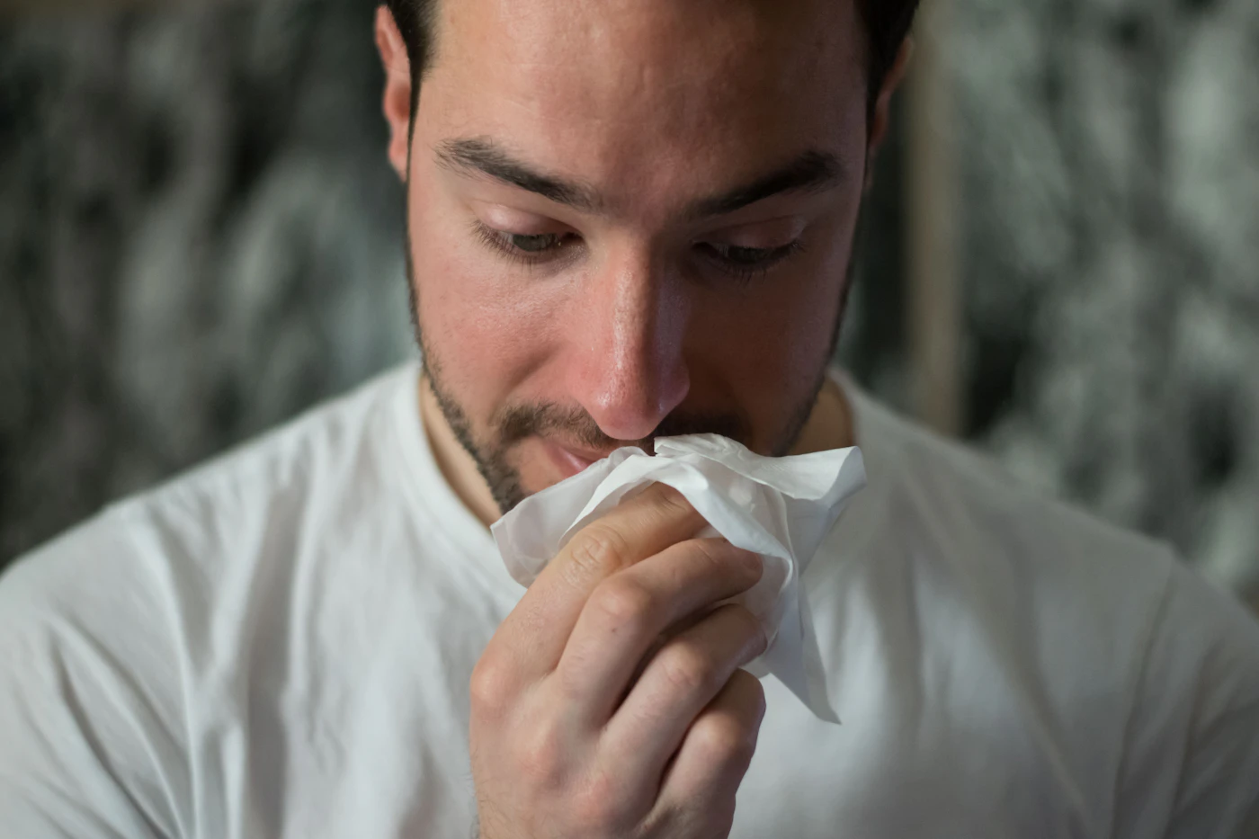Man blowing his nose into a tissue