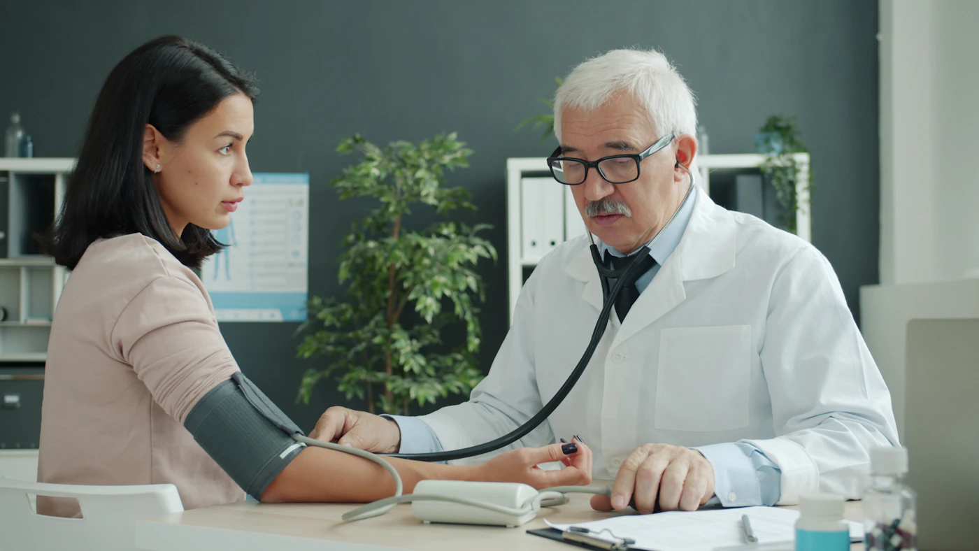 Physician checking a patient's blood pressure with a stethoscope and cuff