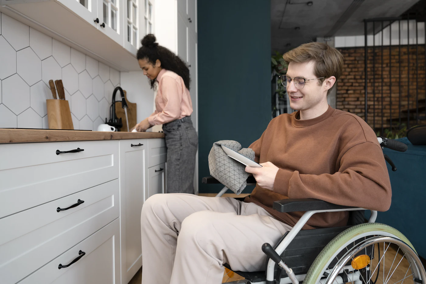 Man in a wheelchair using a tablet in his kitchen at home
