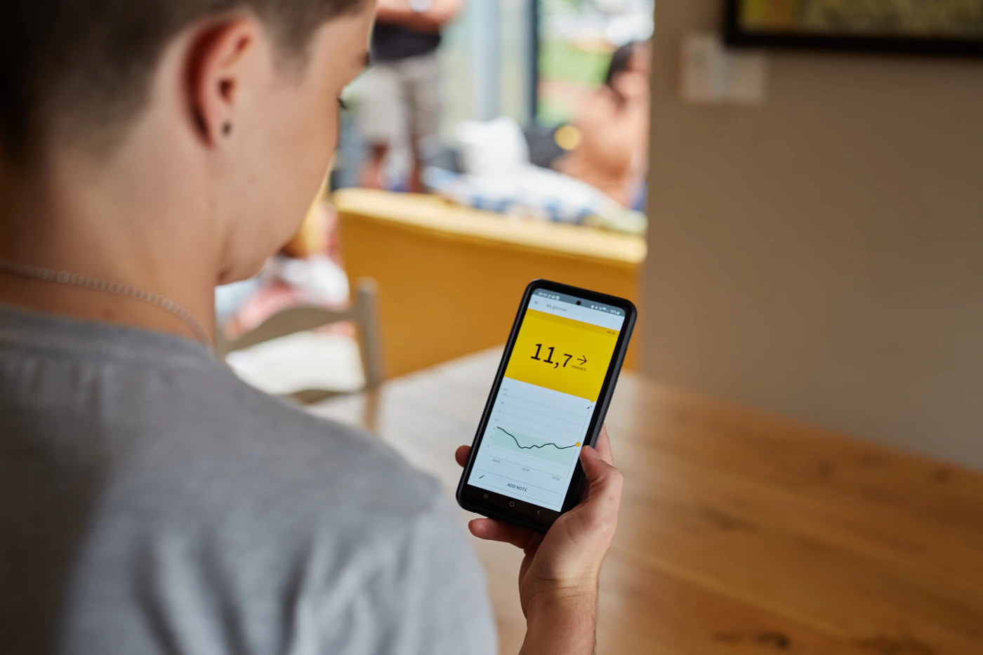 Patient checking glucose monitor readings on a smartphone app