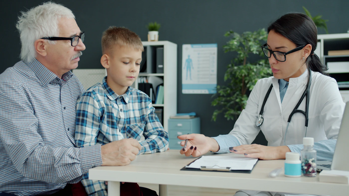Family physician talking with a grandfather and his grandson during an office visit