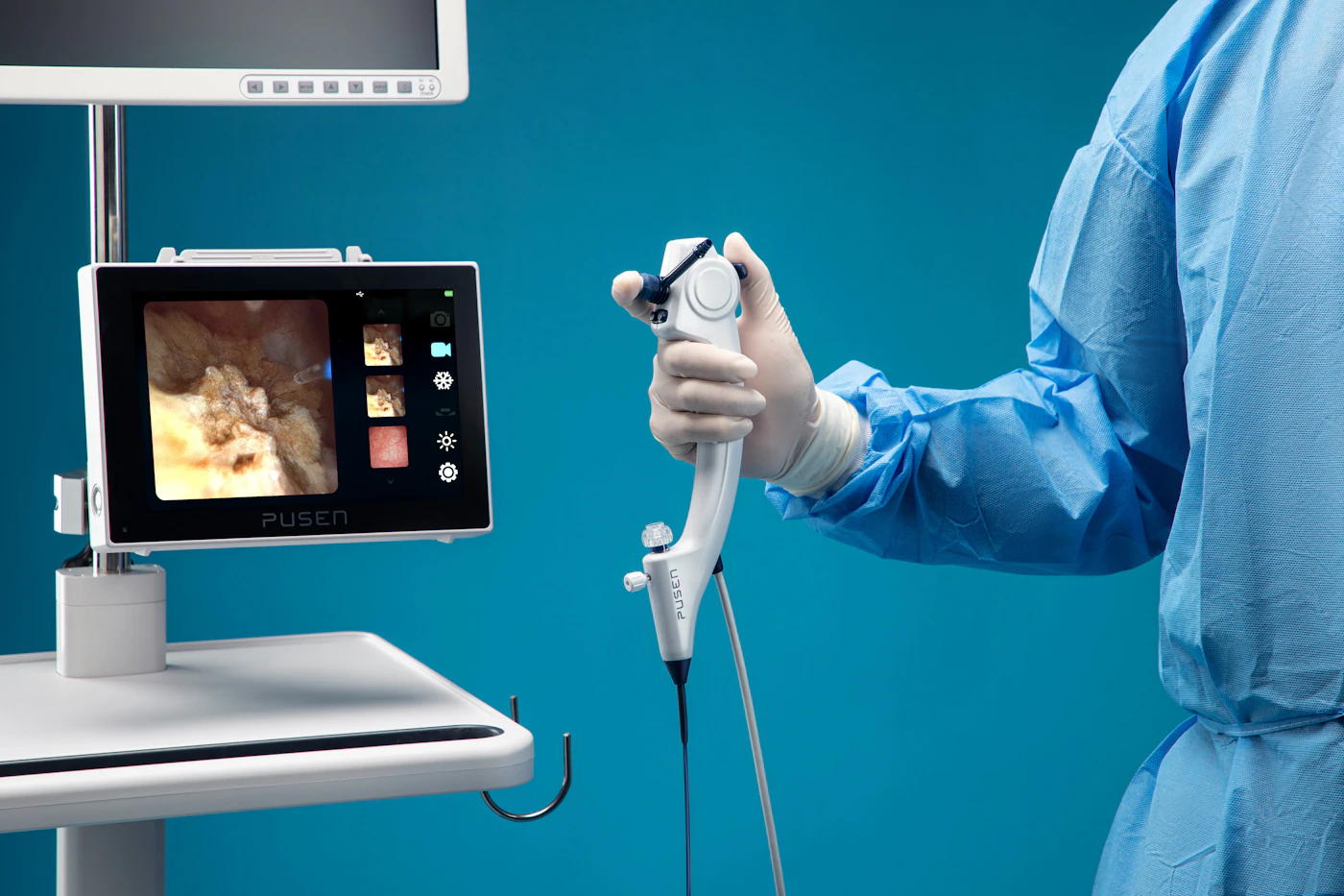 Endoscope held beside a video monitor in a procedure room