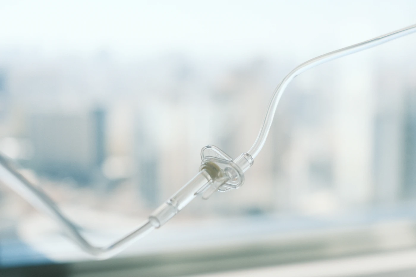 IV infusion line in front of a blurred hospital window