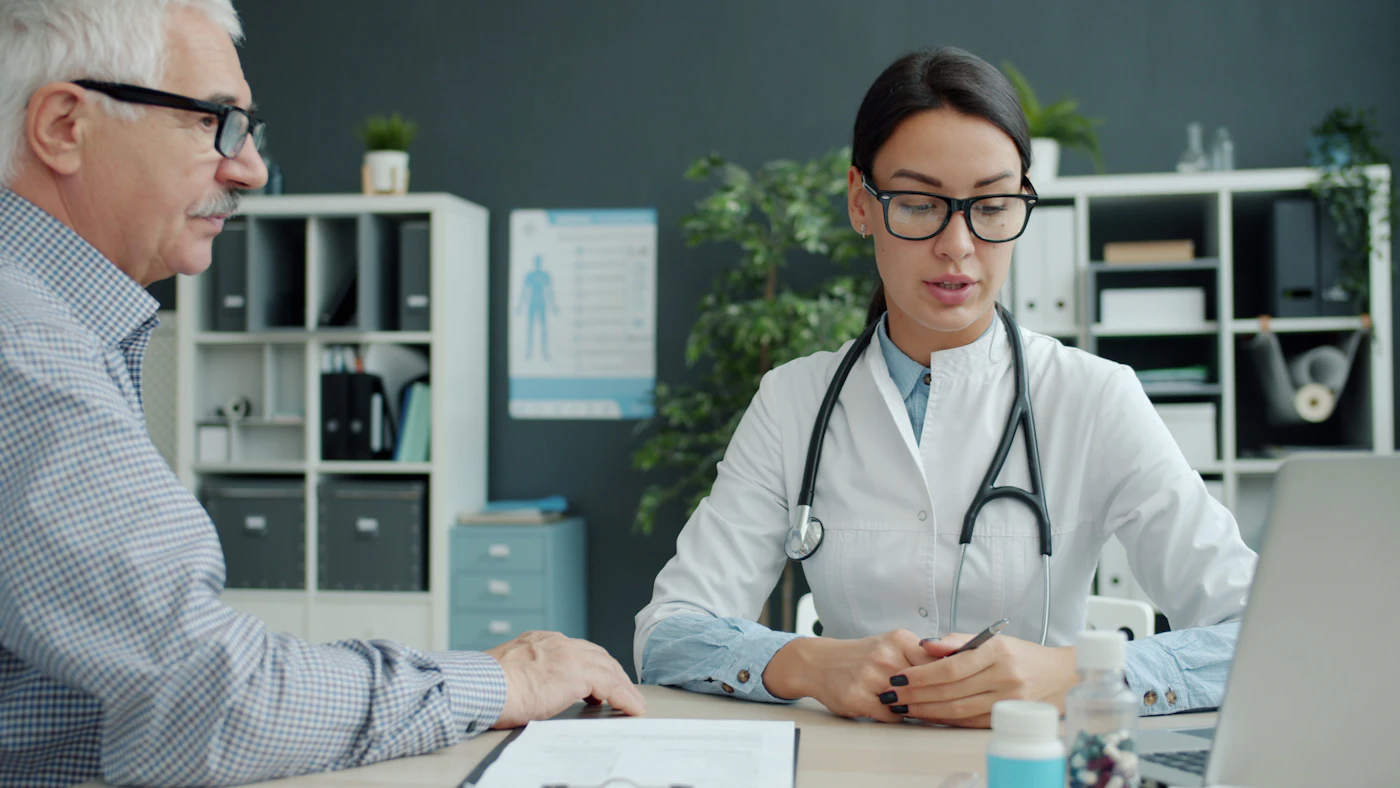 Physician talking with an older patient across her desk during an office visit