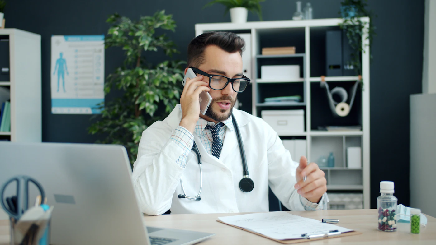 Physician on a phone call at his desk, following up with a patient