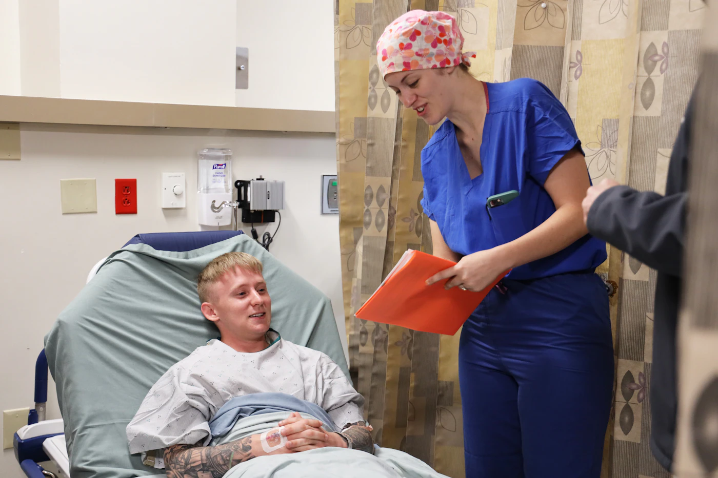 Nurse with a clipboard talking to a patient resting in a treatment chair