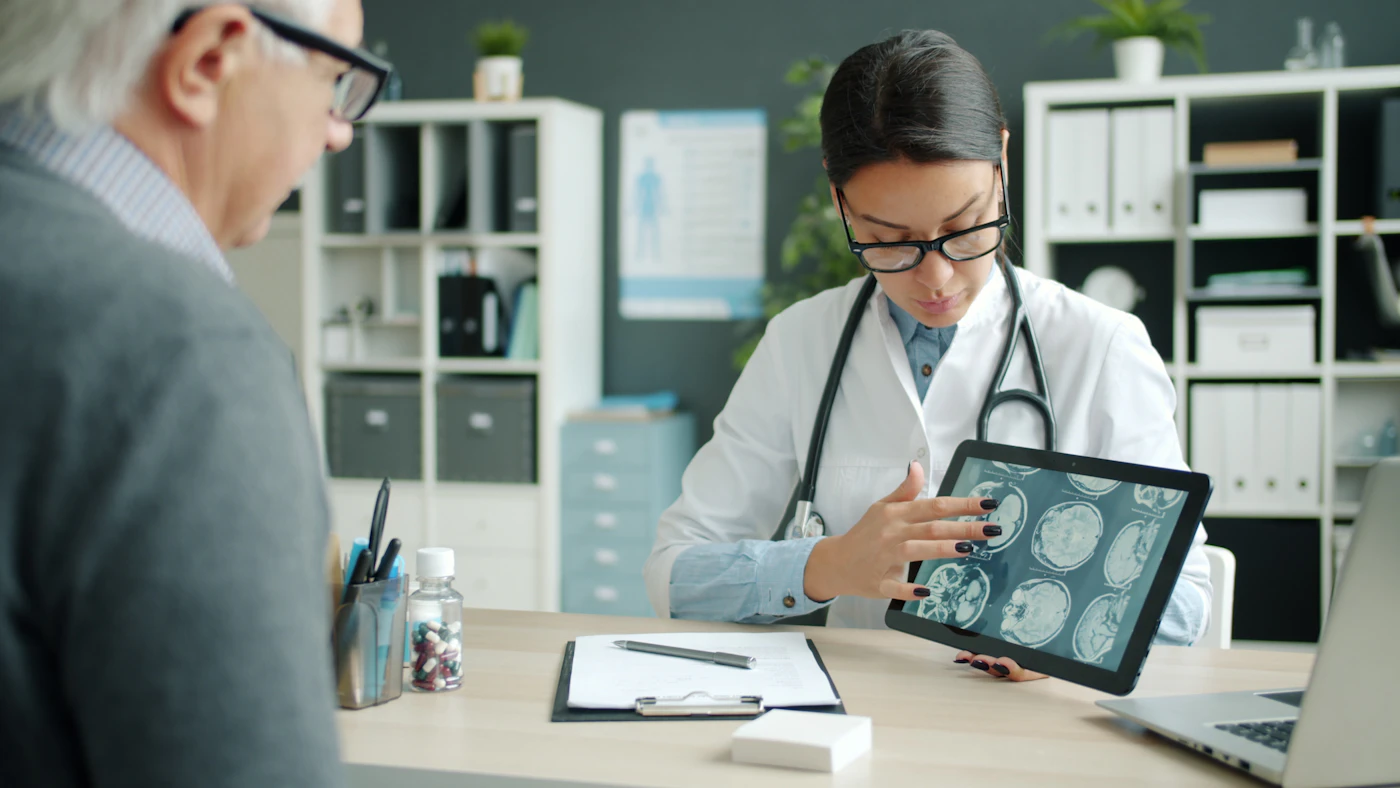 Neurologist showing an older patient brain scan images on a tablet