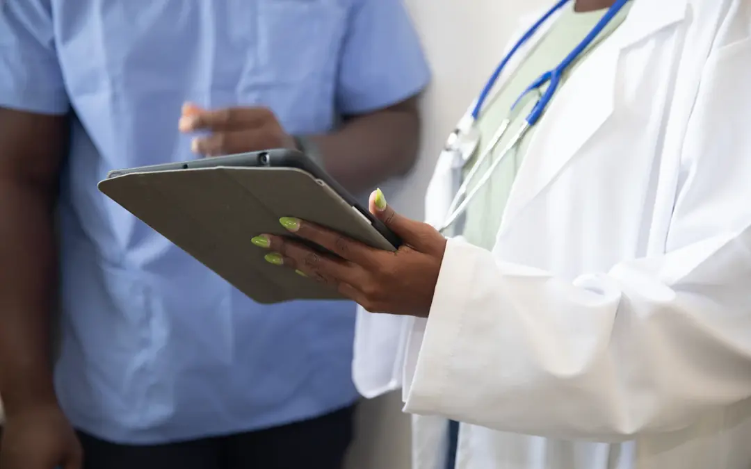 Clinician in a white coat showing information on a tablet to a colleague in scrubs