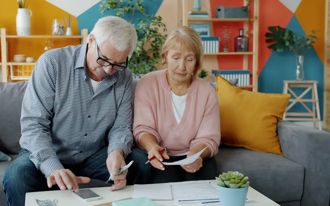 Older couple reviewing bills together on their sofa at home
