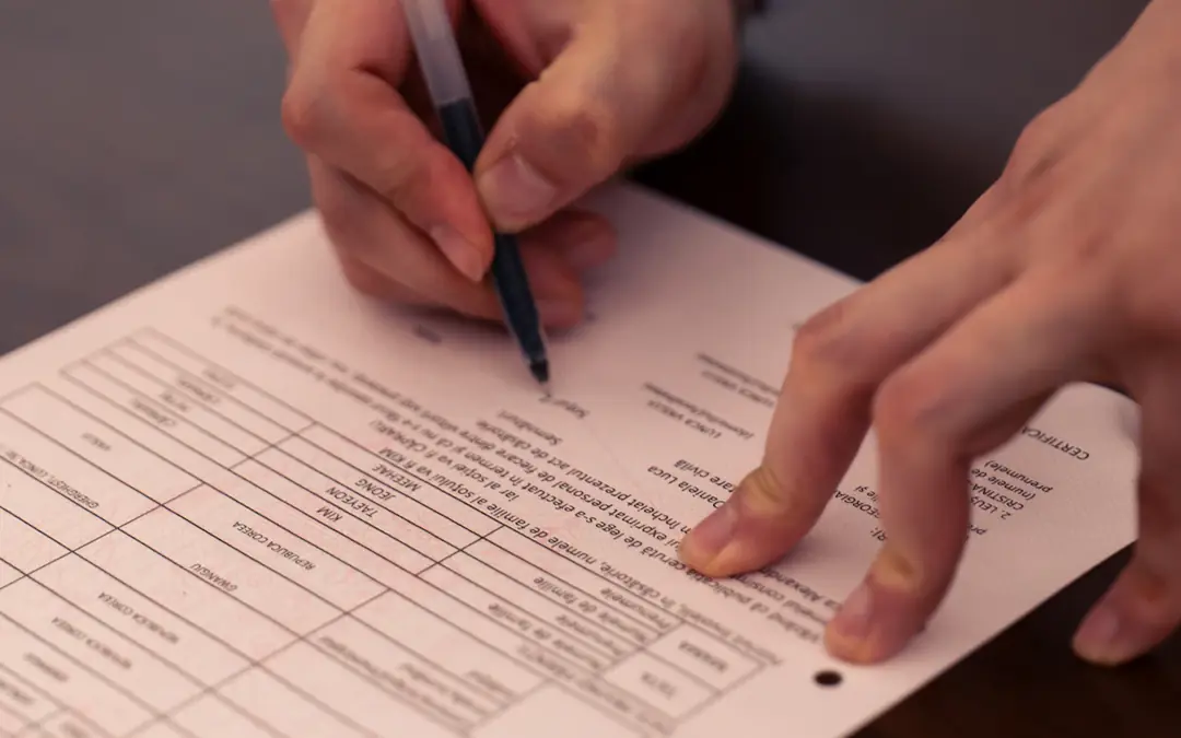 Hands filling in a printed form with a pen
