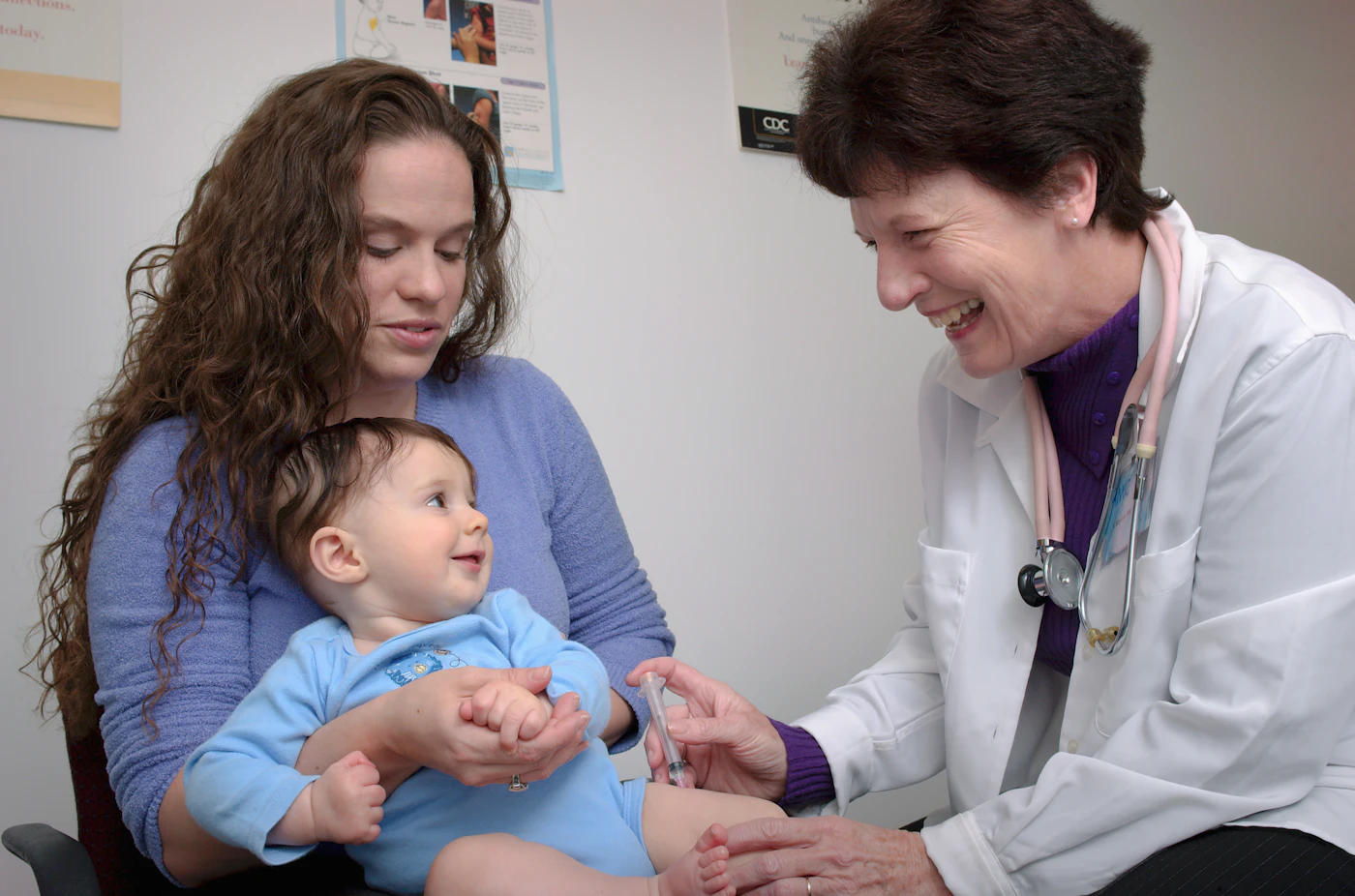 Pediatrician examining a baby held on the mother's lap during a well visit