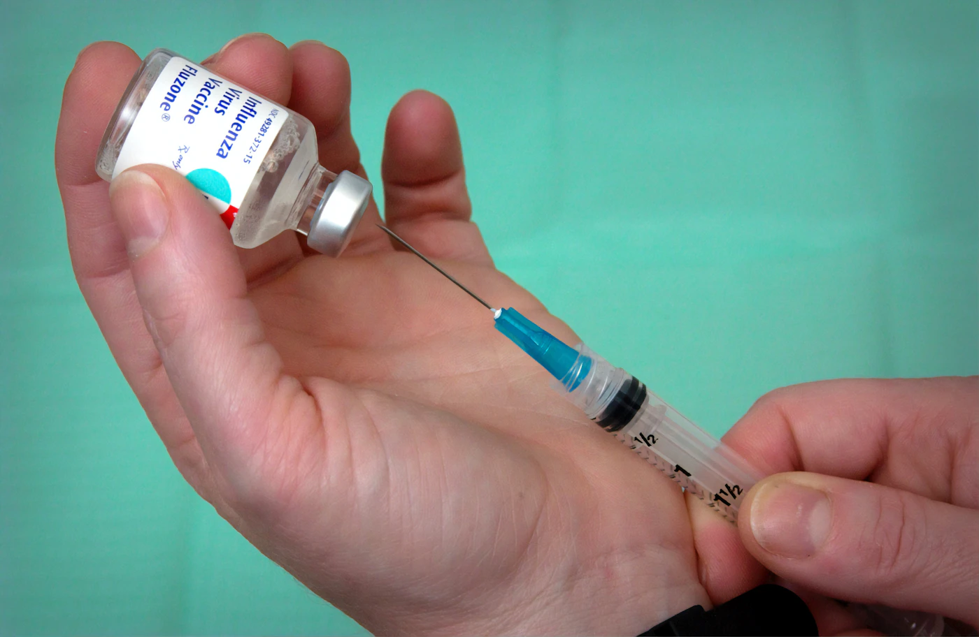 Clinician drawing a vaccine dose from a vial into a syringe