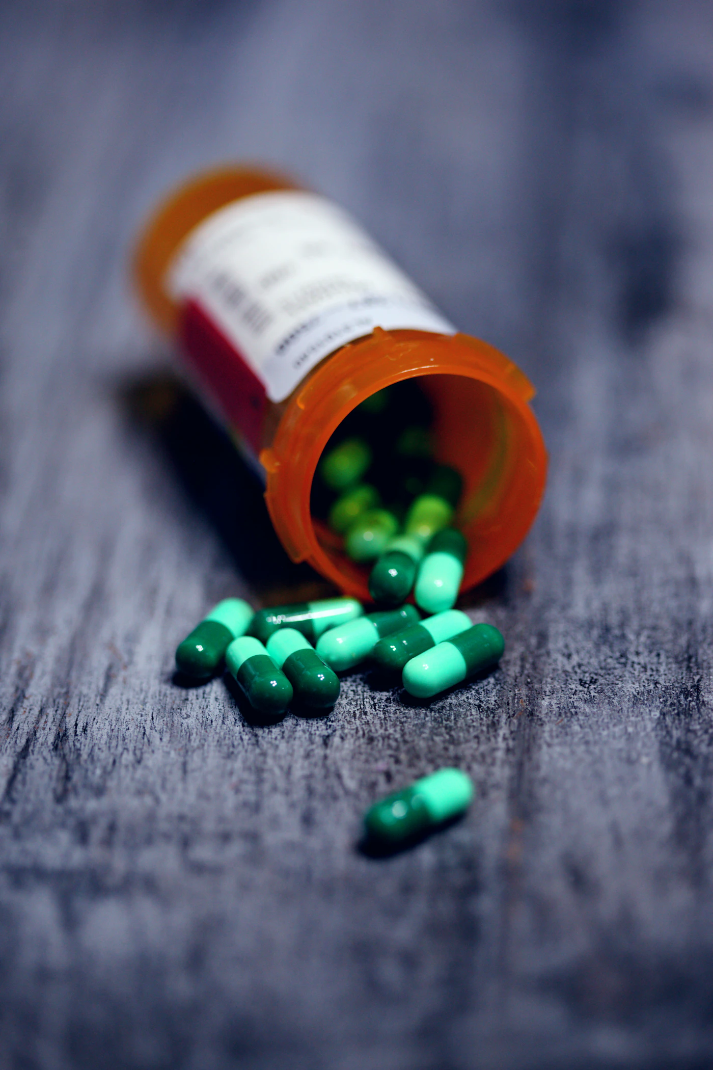 Prescription bottle tipped over with capsules spilling onto a table