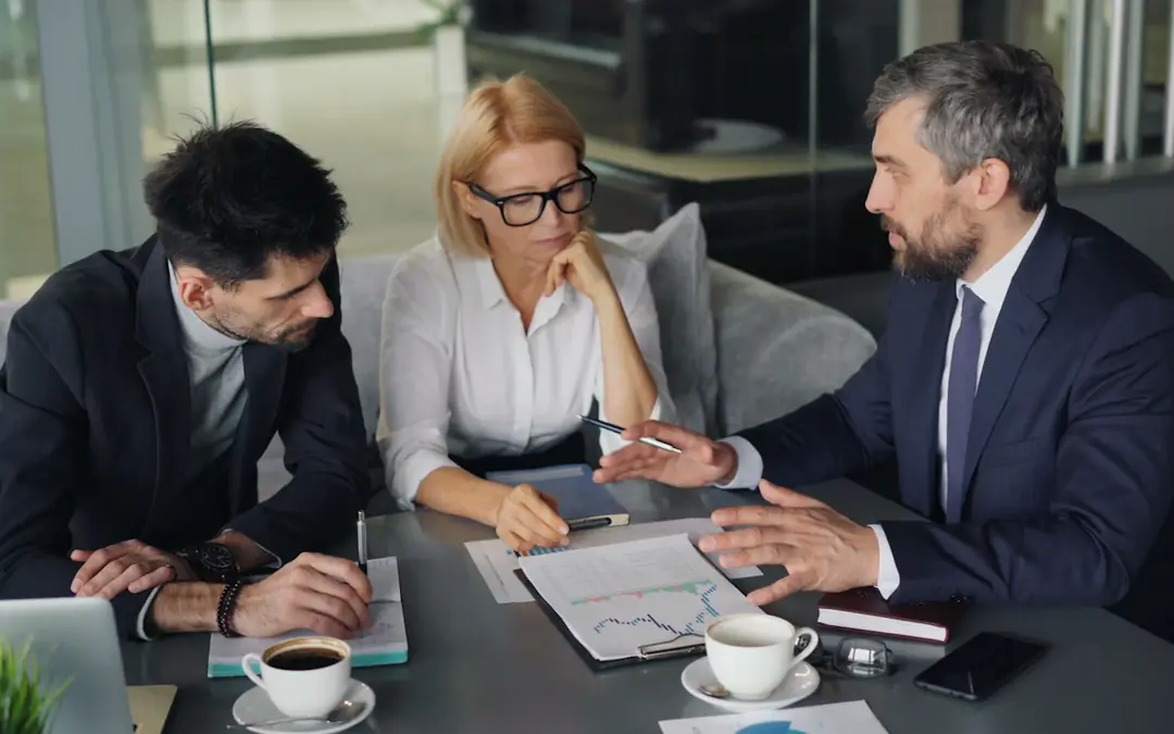 Three people reviewing financial charts at a meeting table