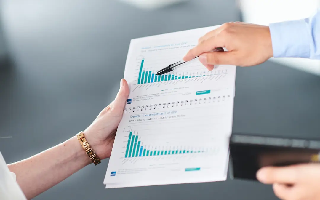 Two people reviewing a printed revenue report with bar charts